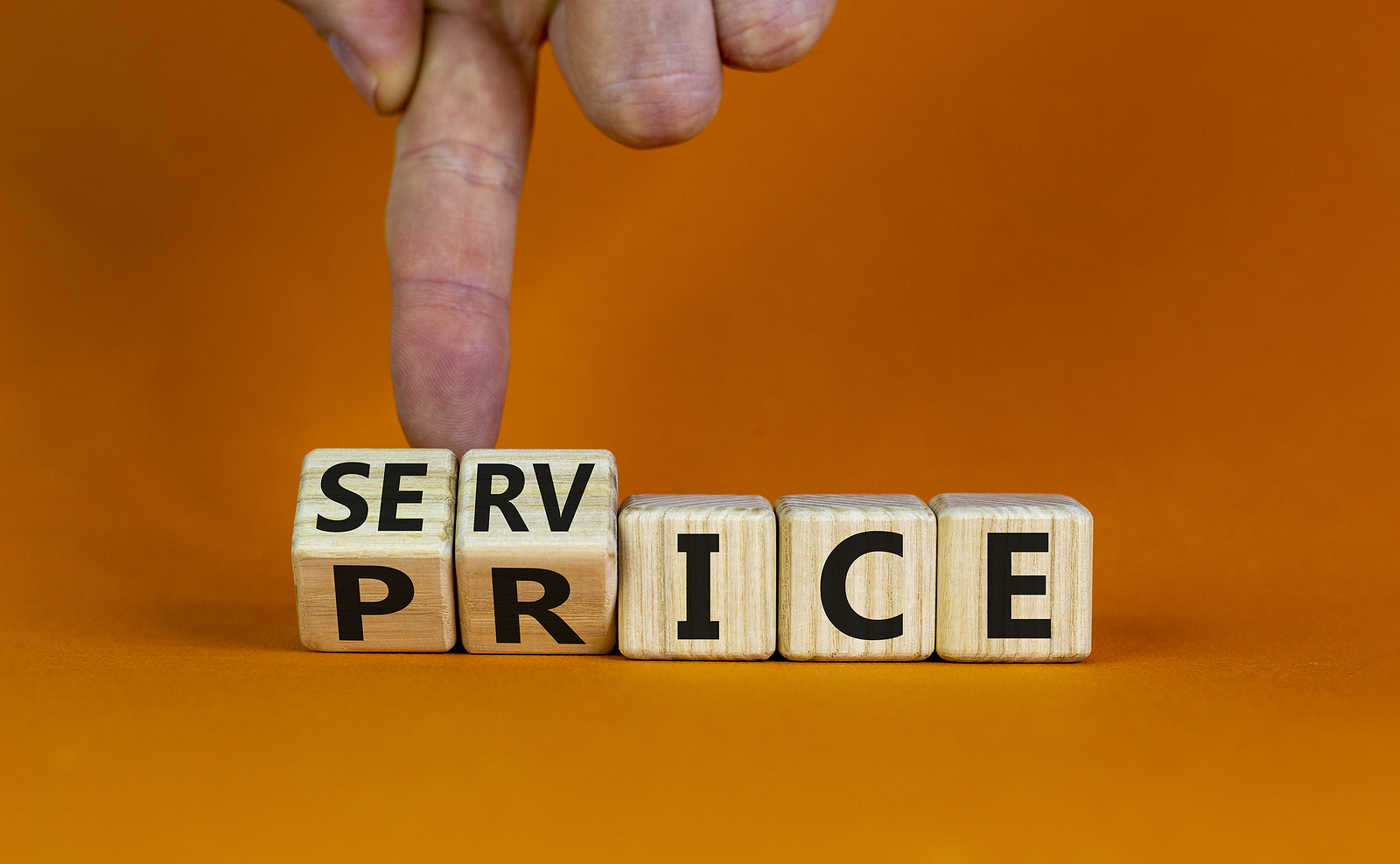 Service price symbol. Hand turns a cube and changes the words 'service' to 'price'. Beautiful orange background. Business and service price concept
