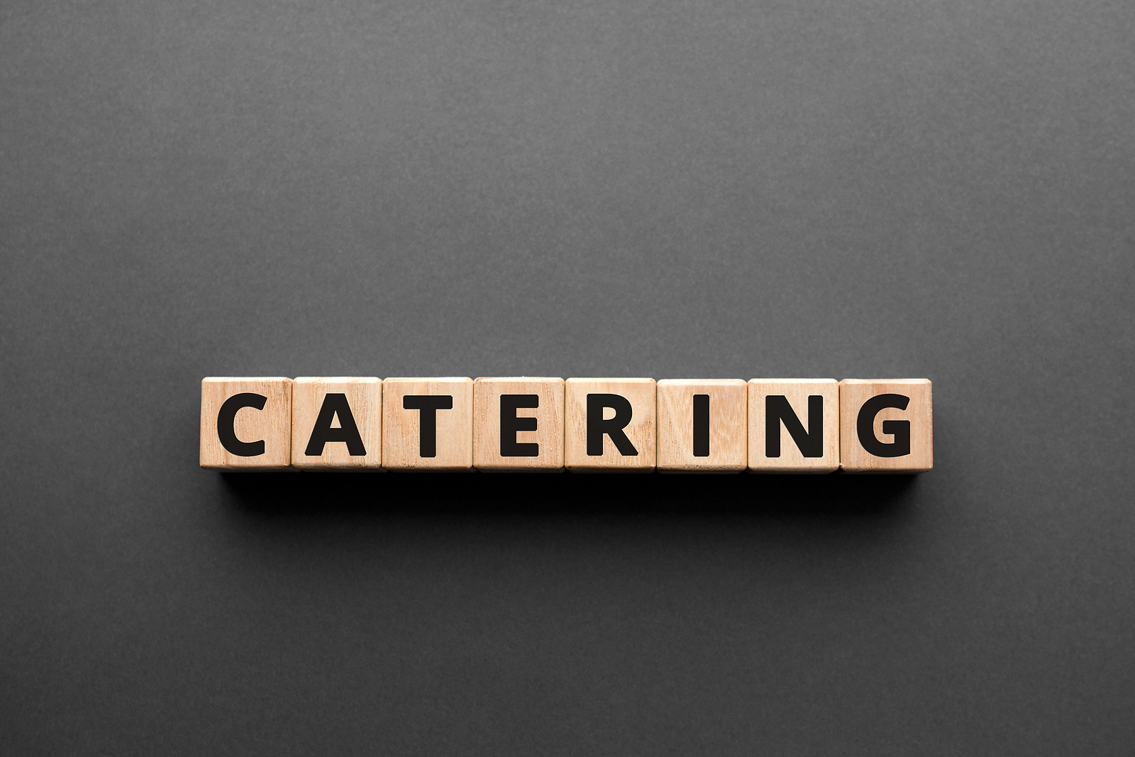 Catering - words from wooden blocks with letters, making or serving food catering concept, top view gray background