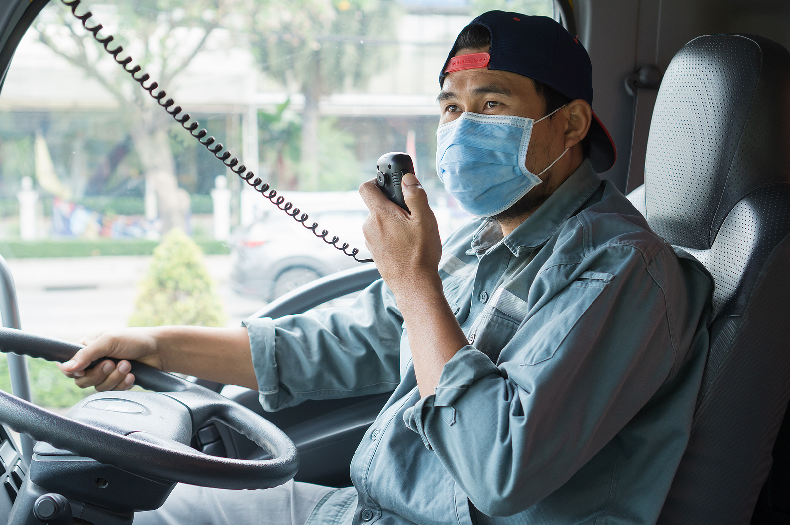 Quality truck driver wearing a protective mask while driving his truck.