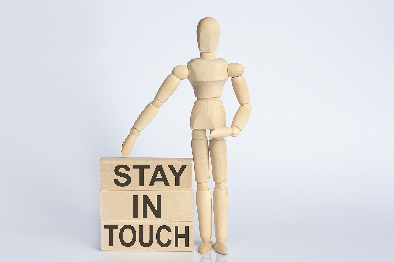 Wooden man shows with hand text Stay In Touch concept on wooden block